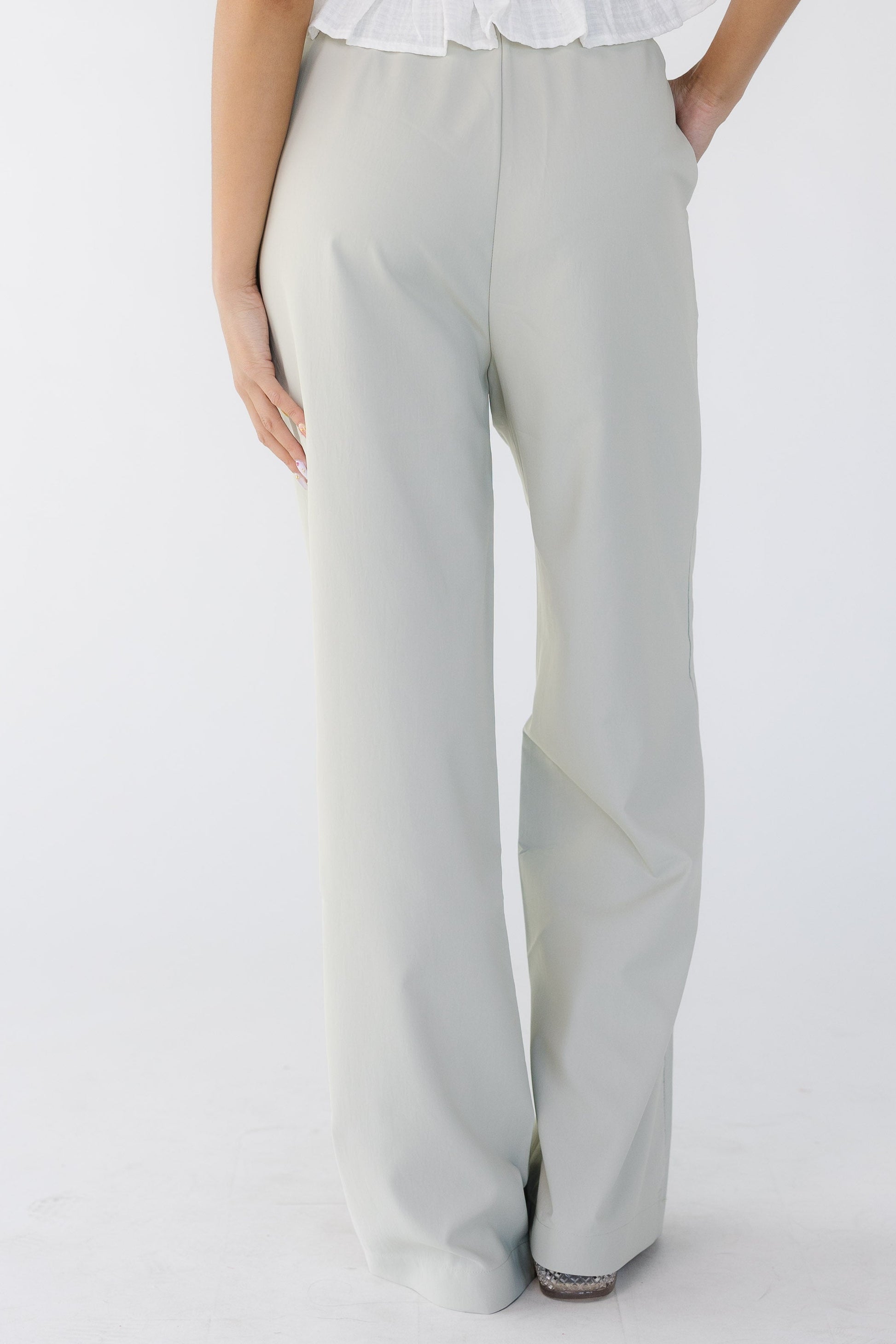 Back view of a young woman wearing taupe-grey wide leg pants.