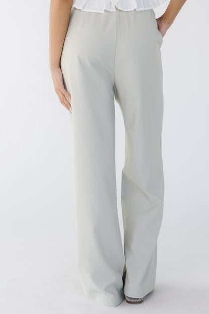 Back view of a young woman wearing taupe-grey wide leg pants.