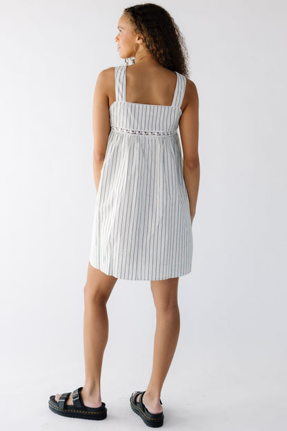 Back view of a teenage girl wearing an off white and black stripe jumper with wide straps and lace inset around the bottom of the bodice.