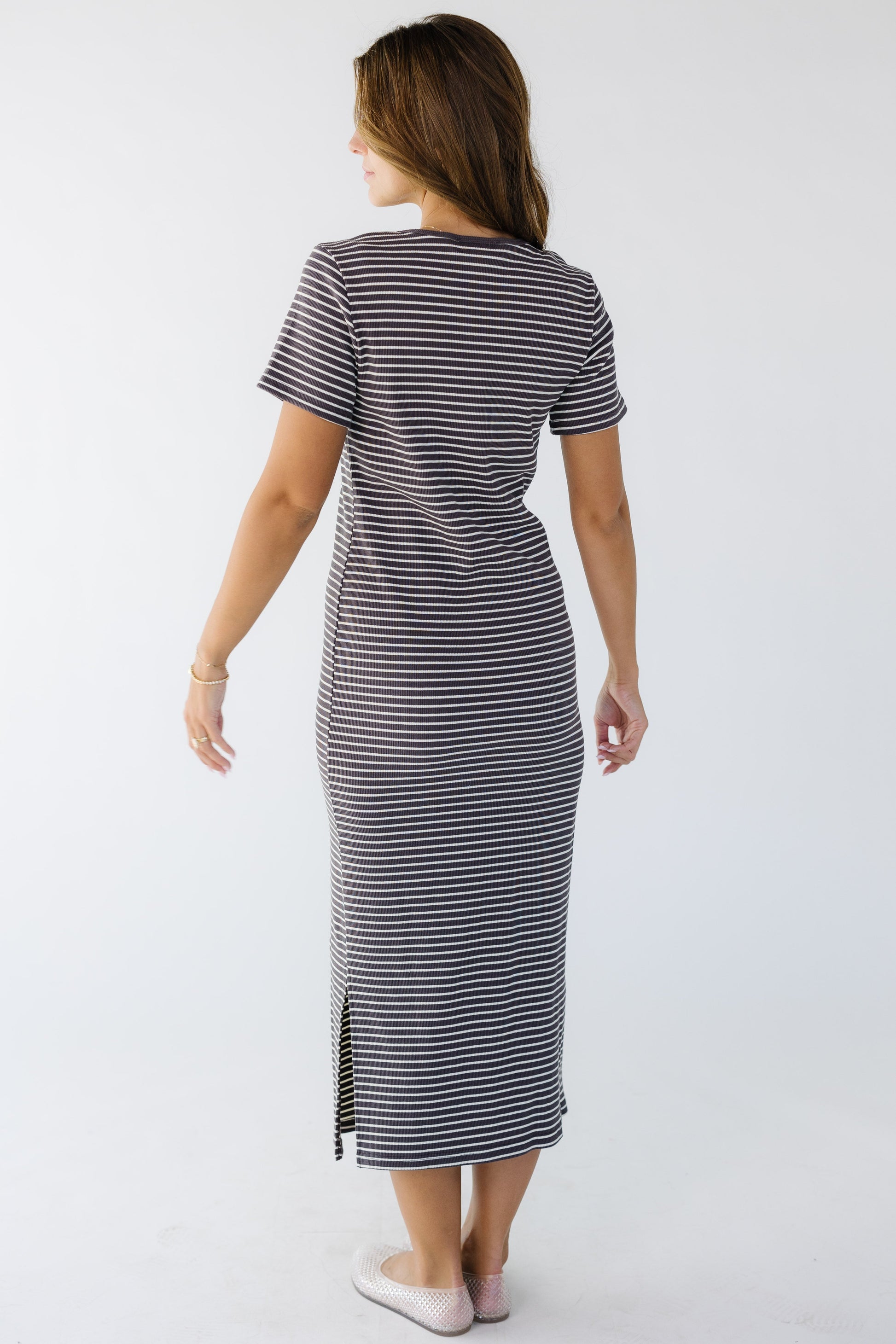 Back view of a woman wearing a stretchy rib knit midi dress in brown and white stripe with short sleeves.