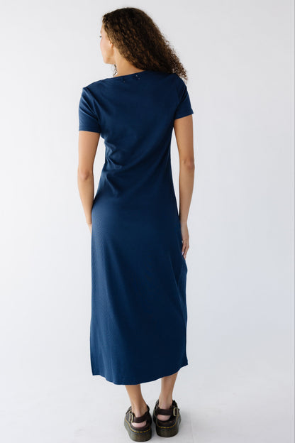 Back view of a teenage girl wearing a navy close fitting rib knit dress with short sleeves.