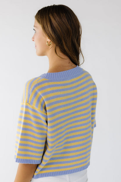 Back view of a young woman wearing a loose fitting cardigan in light blue and yellow.