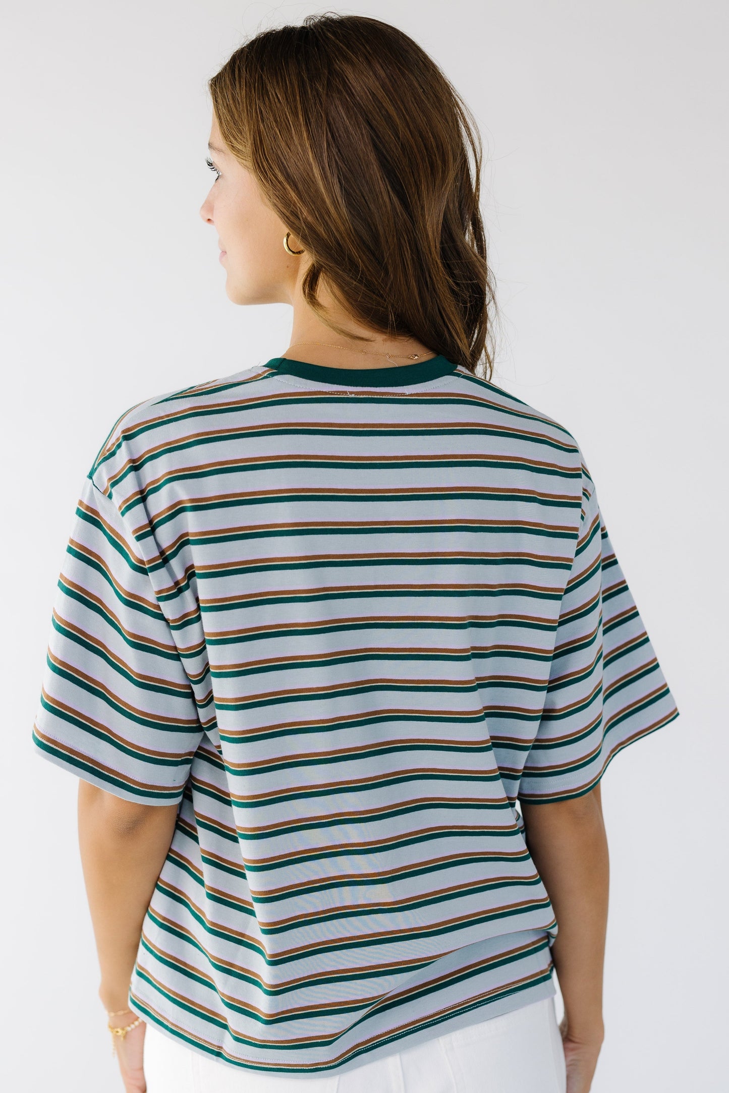 Back view of a young woman wearing a  light blue with brown & green paired stripes.
