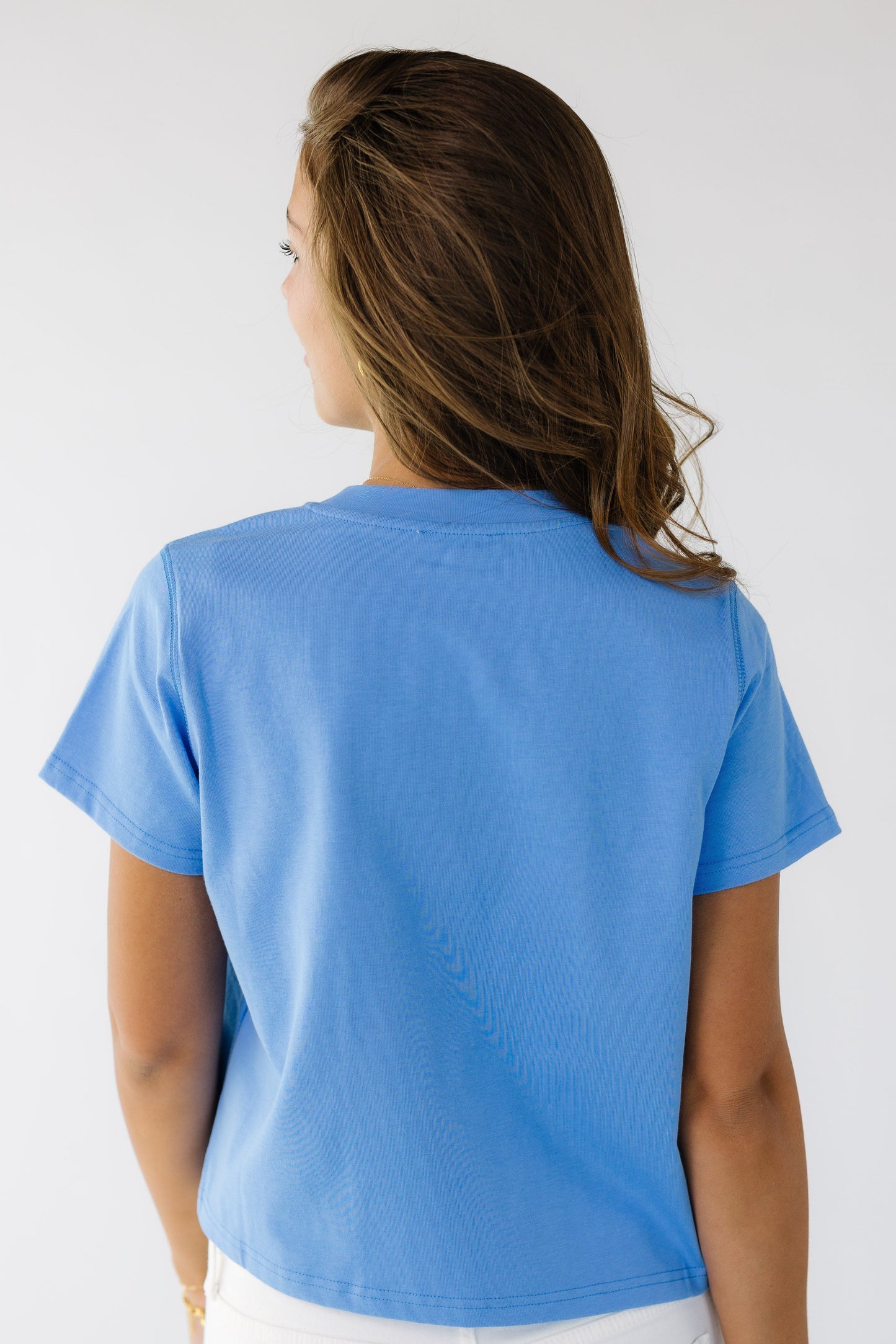Back view of a young woman wearing a blue short sleeve teen.