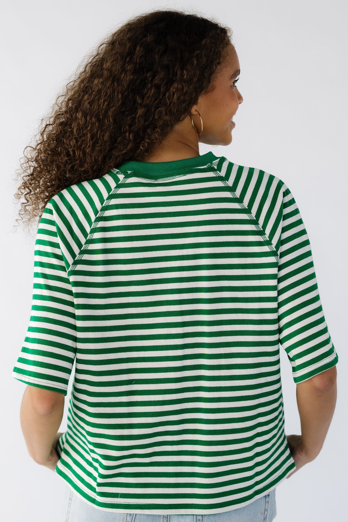 Back view of a teen girl wearing a loose  fitting tee in green and white.