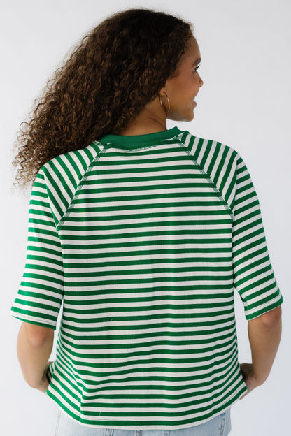 Back view of a teen girl wearing a loose  fitting tee in green and white.