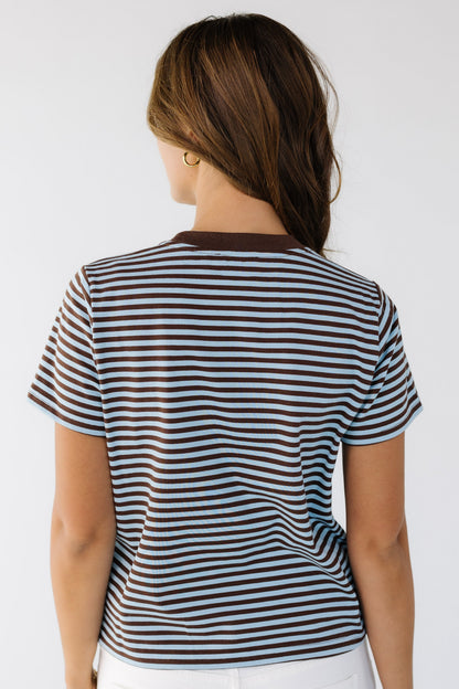 Back view of a woman wearing a short sleeve brown and blue stripe tee.