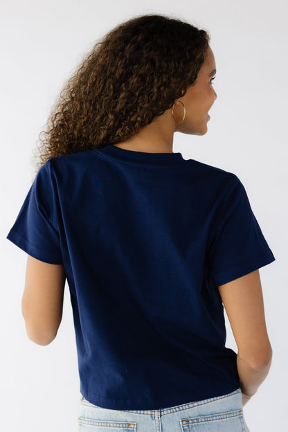 Back view of a teen girl wearing a short sleeve navy tee.