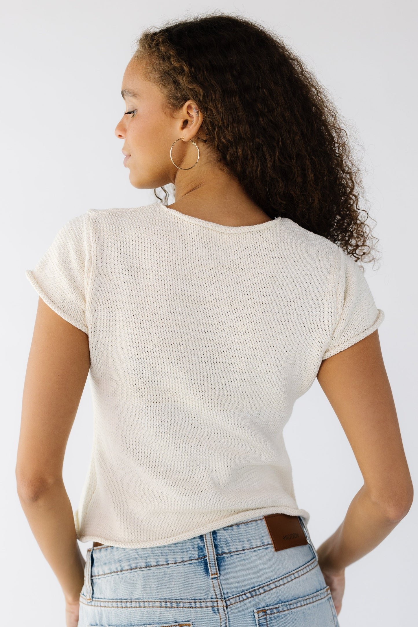 Back view of a teen girl wearing a light weight sweater the short sleeves.