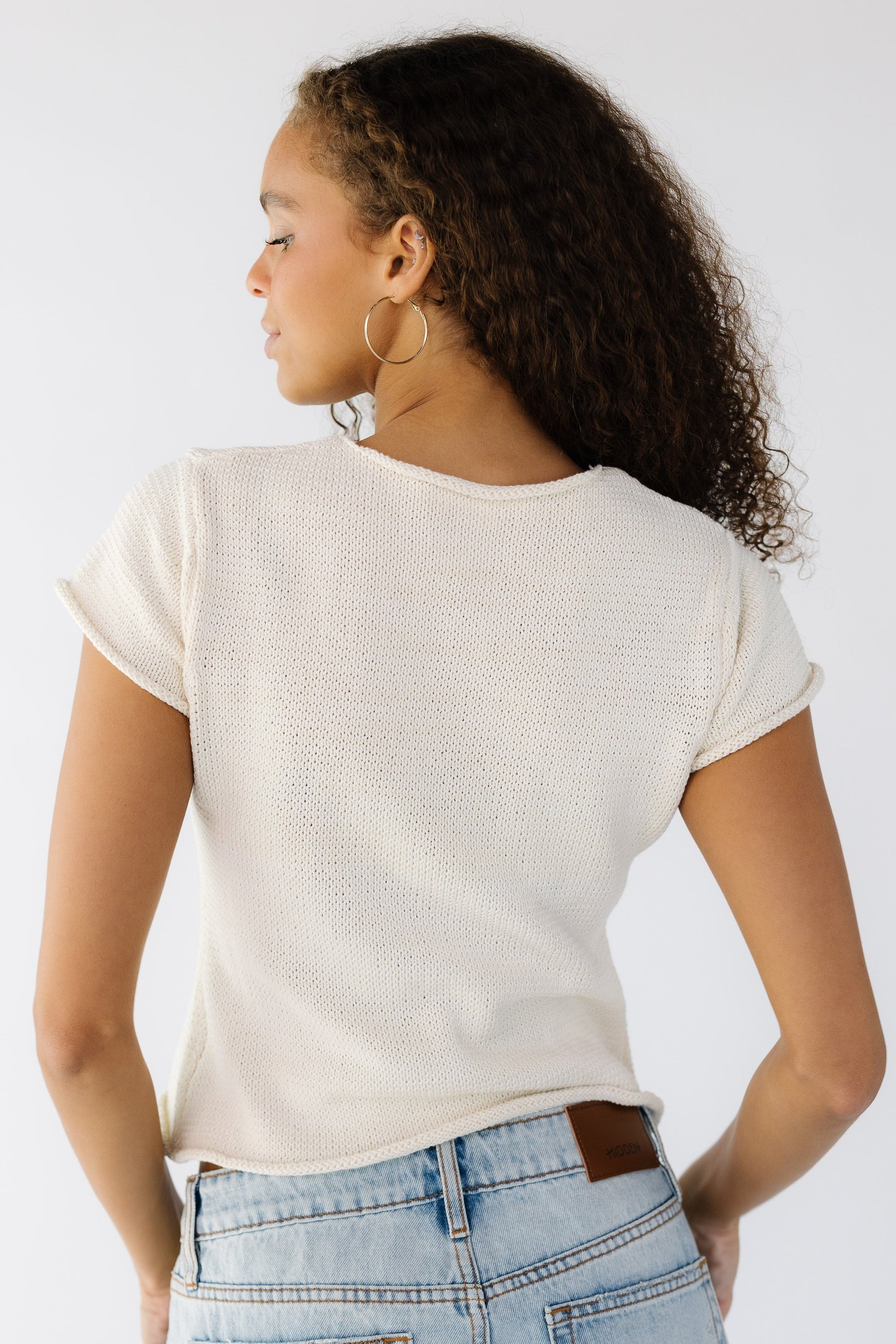 Back view of a teen girl wearing a light weight sweater the short sleeves.