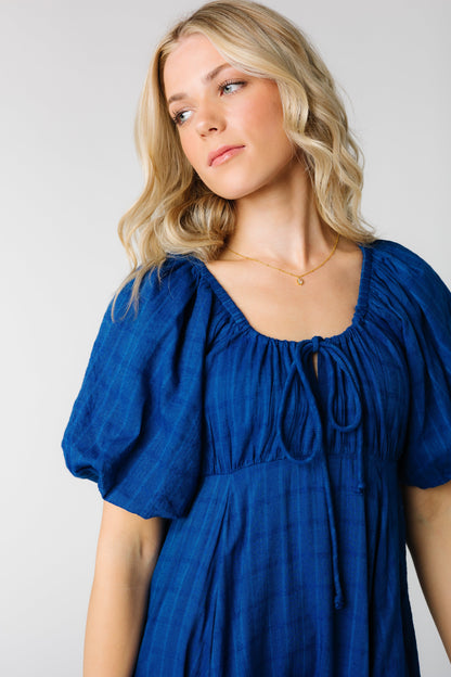 Close view of blue textured dress with round neckline and front tie