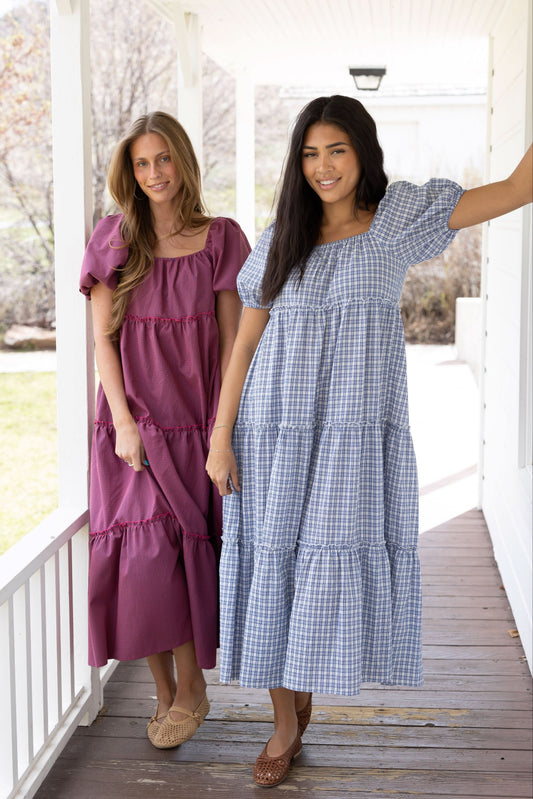 2 young women wearing modest tiered gingham midi dresses with a square neckline and balloon sleeves.