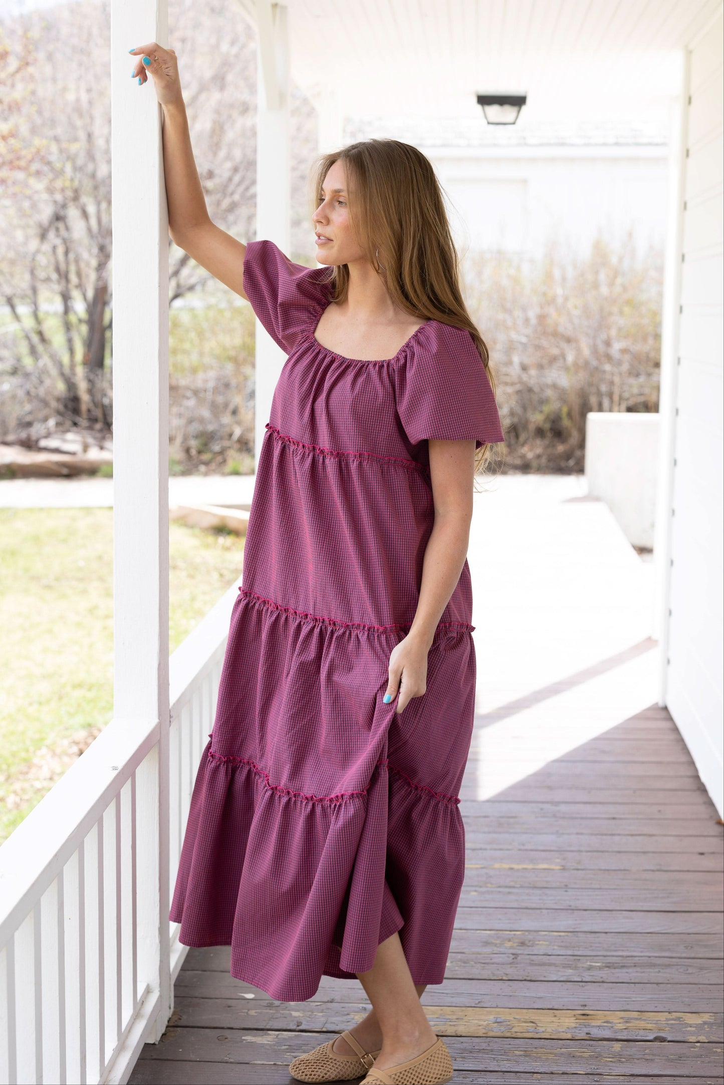 Young woman wearing a modest red and navy loose fitting tiered midi dress with balloon sleeves and a square elastic neckline. 