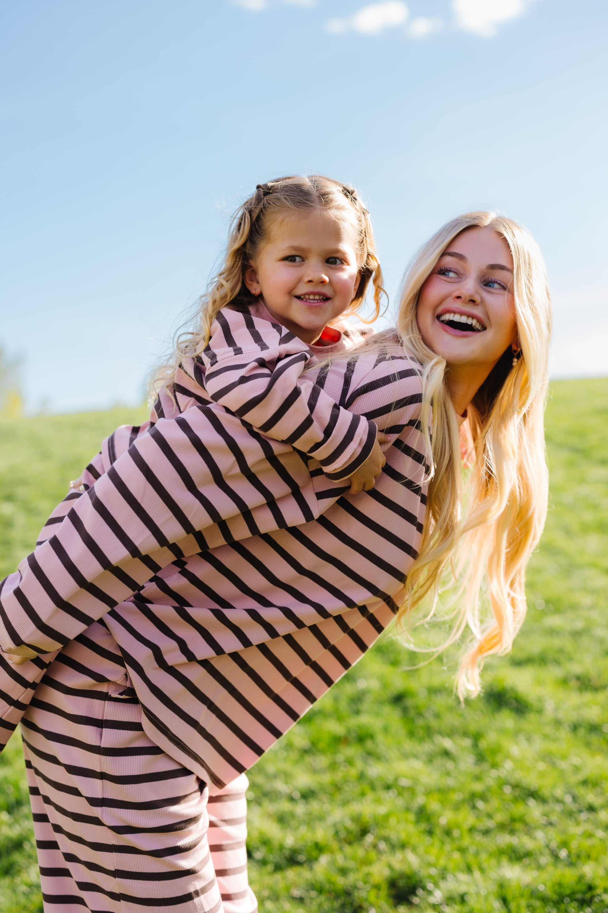 Young woman and little girl in modest loose fitting lounge sets in pink and brown stripe.