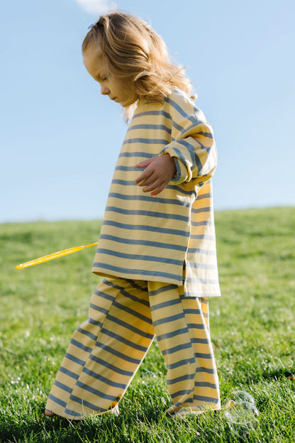 Little girl wearing a cotton ribbed modest yellow & blue stripe lounge set with wide long leg pants and long sleeves.