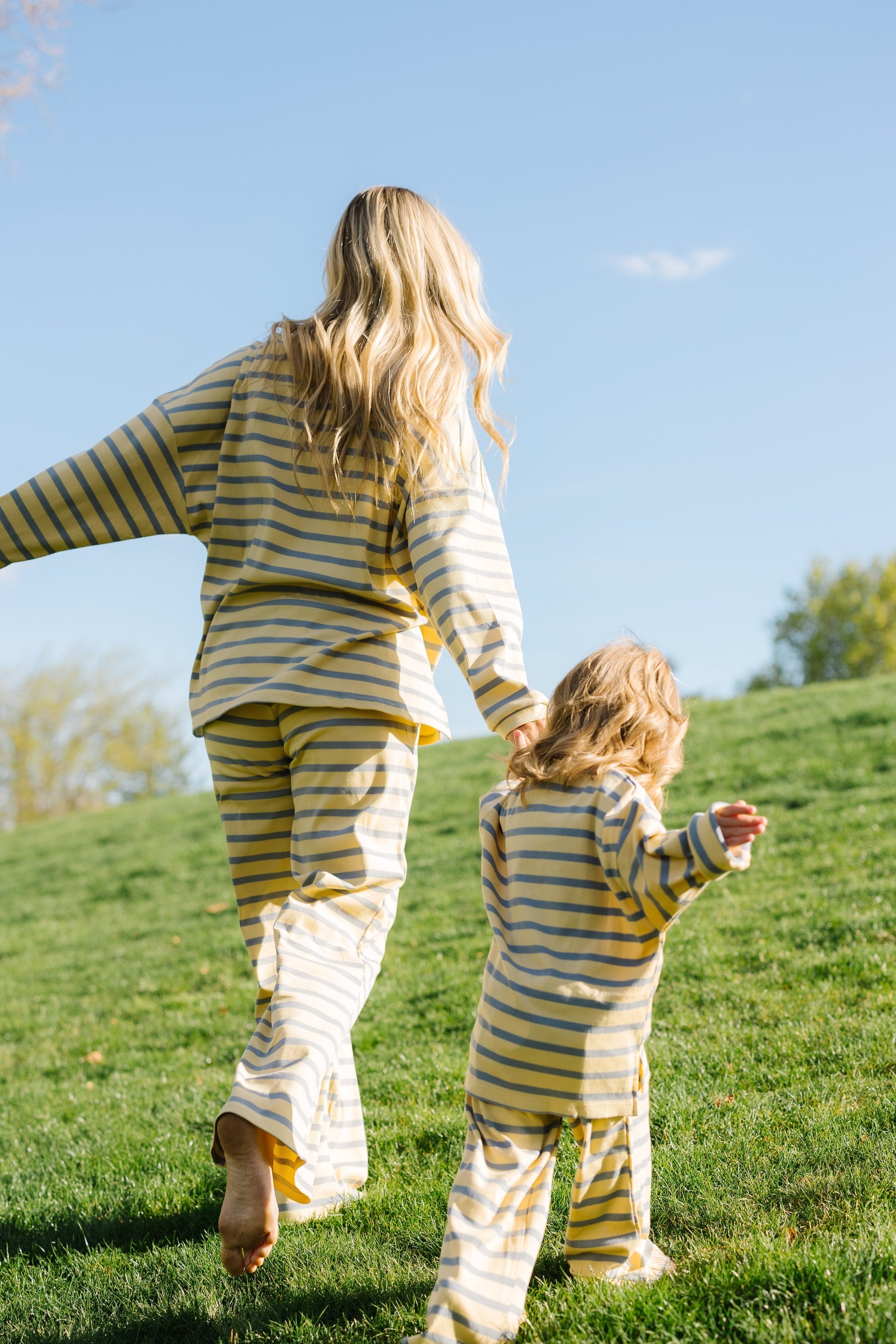 Back view of a woman and little girl wearing modest yellow & blue stripe matching lounge sets.