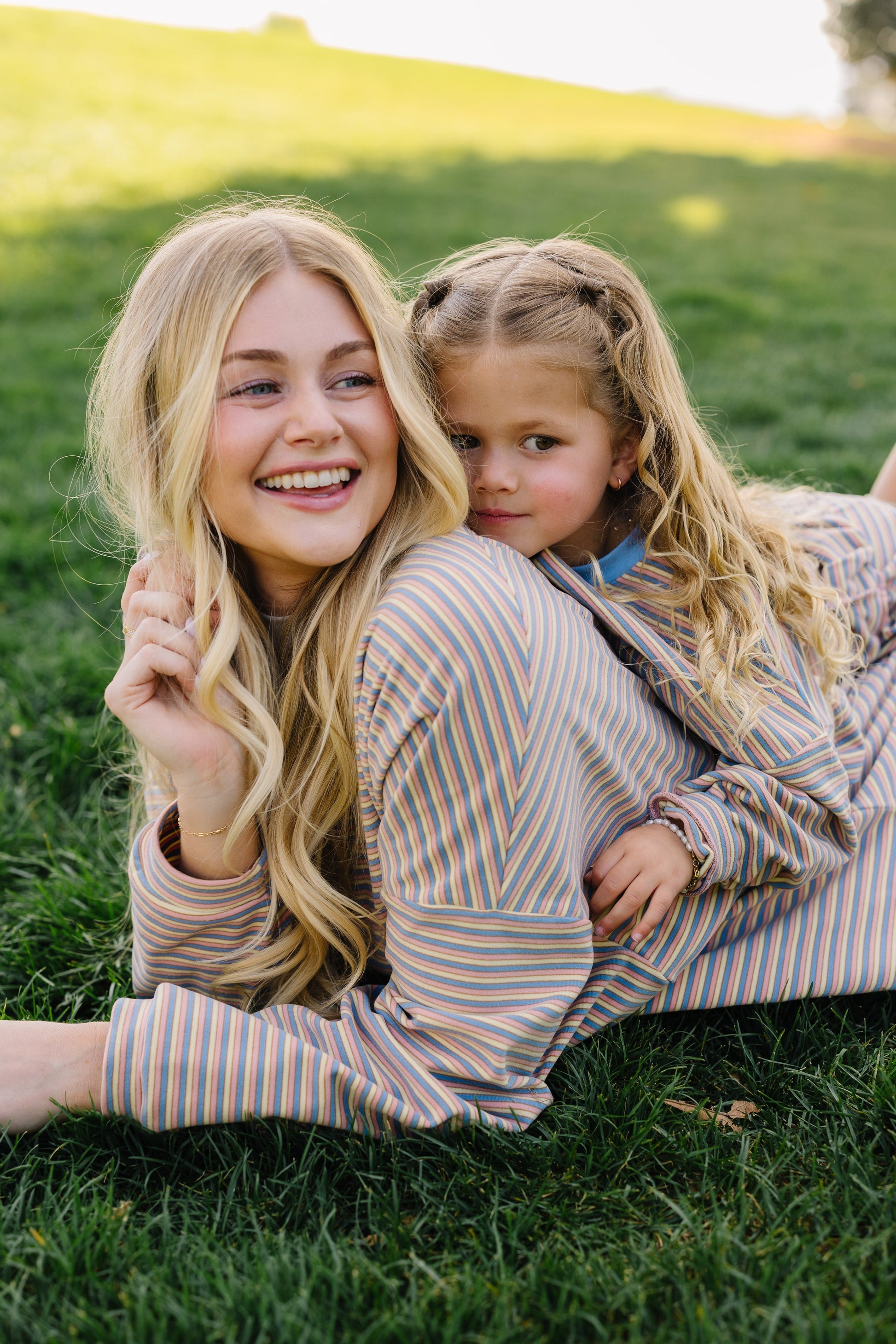 Woman and little girl wearing matching loose fitting lounge sets in cream, blue & pink stripe.