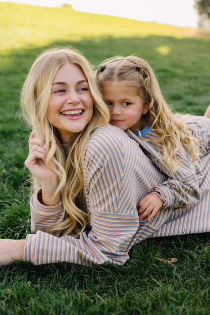 Woman and little girl wearing matching loose fitting lounge sets in cream, blue & pink stripe.