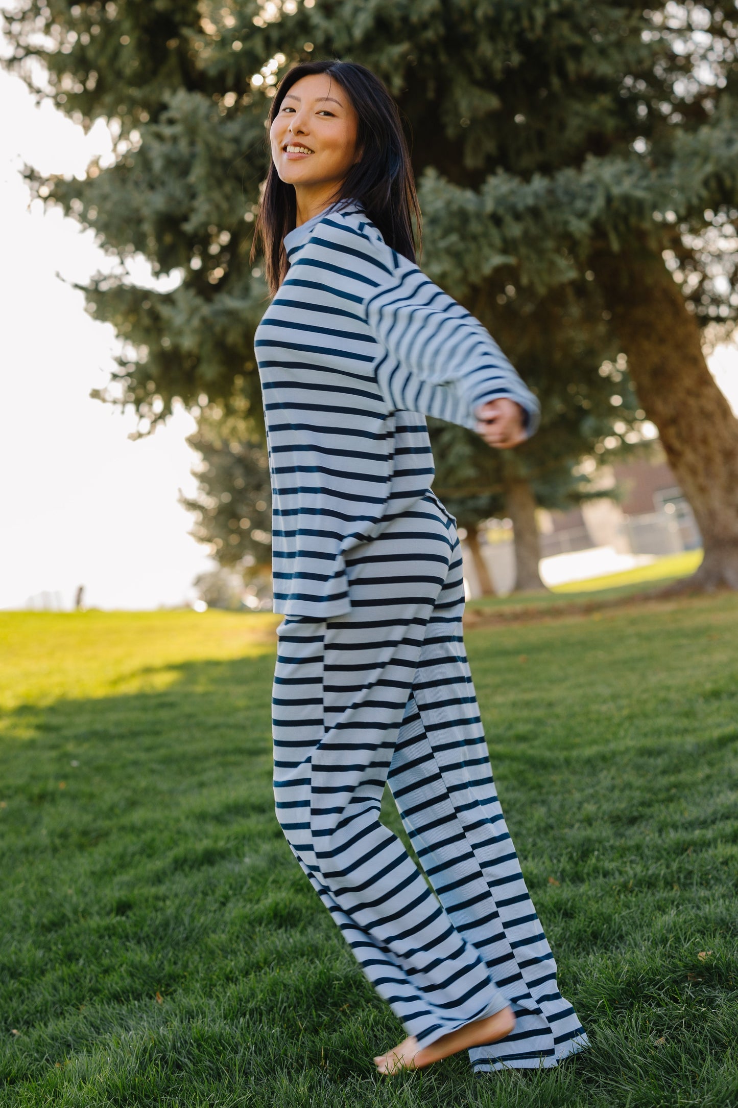 Young woman wearing a light blue and dark blue, loose fitting lounge set with long sleeves and wide leg pants.