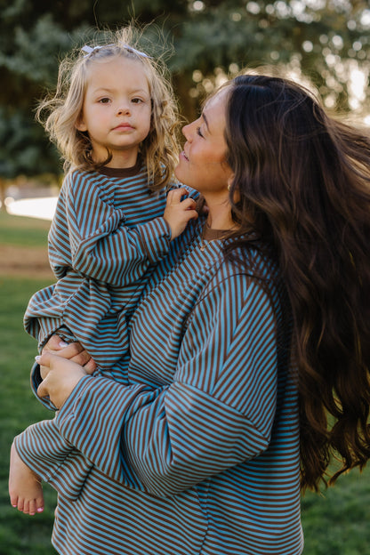 Adult and little girl wearing matching lounge sets in blue and brown with long sleeves and a crew neckline.