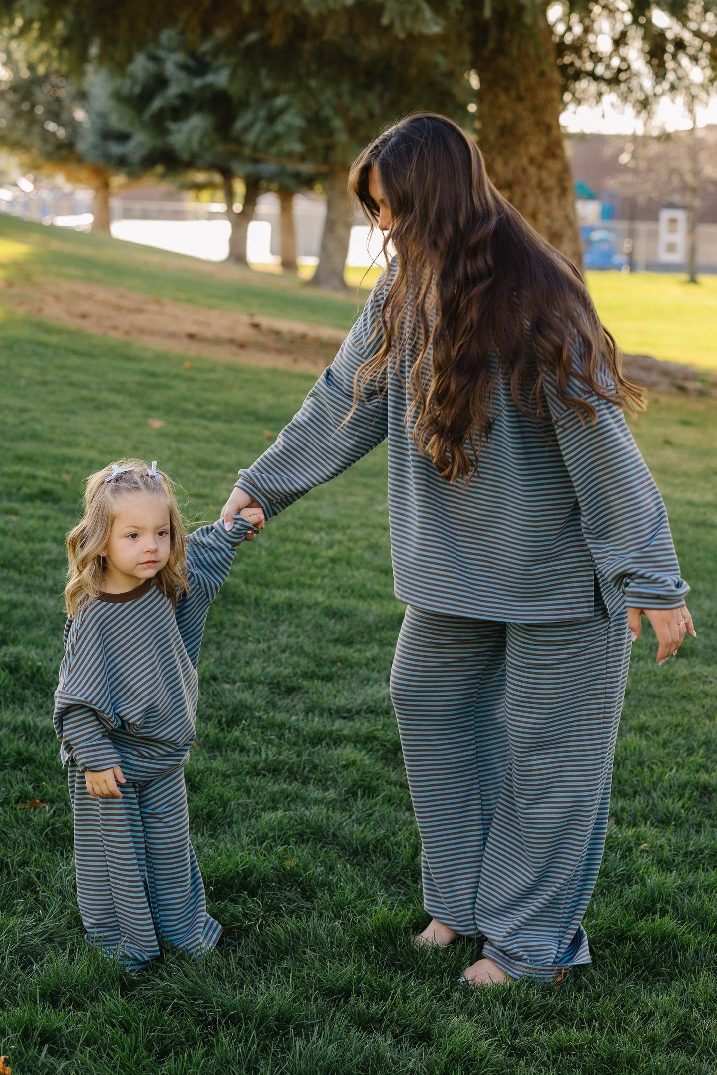 Little girl and woman wearing loose fitting, matching blue & brown stripe lounge sets.