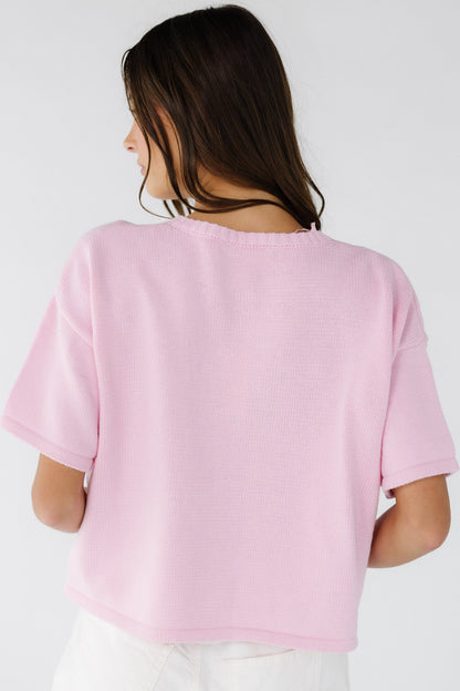 Back view of a woman wearing a pink short sleeve sweater.