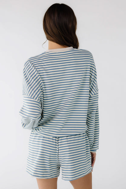 Back view of a woman wearing a cream & blue stripe loose fitting shorts set.