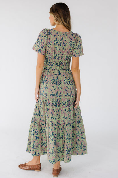 Back view of a woman wearing a green print midi-maxi dress with short sleeves.
