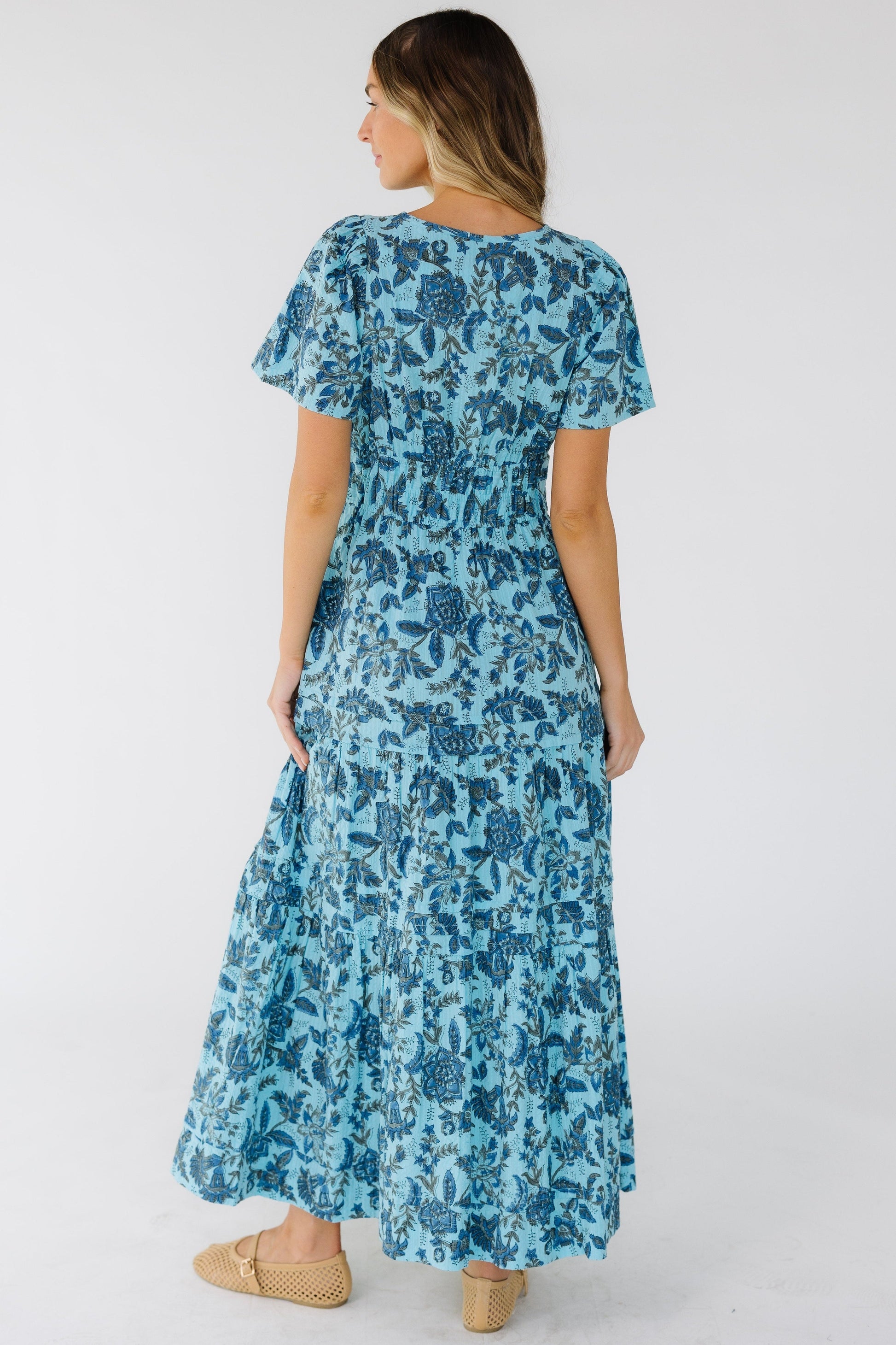 Back view of a woman wearing a blue print midi-maxi dress with short sleeves.