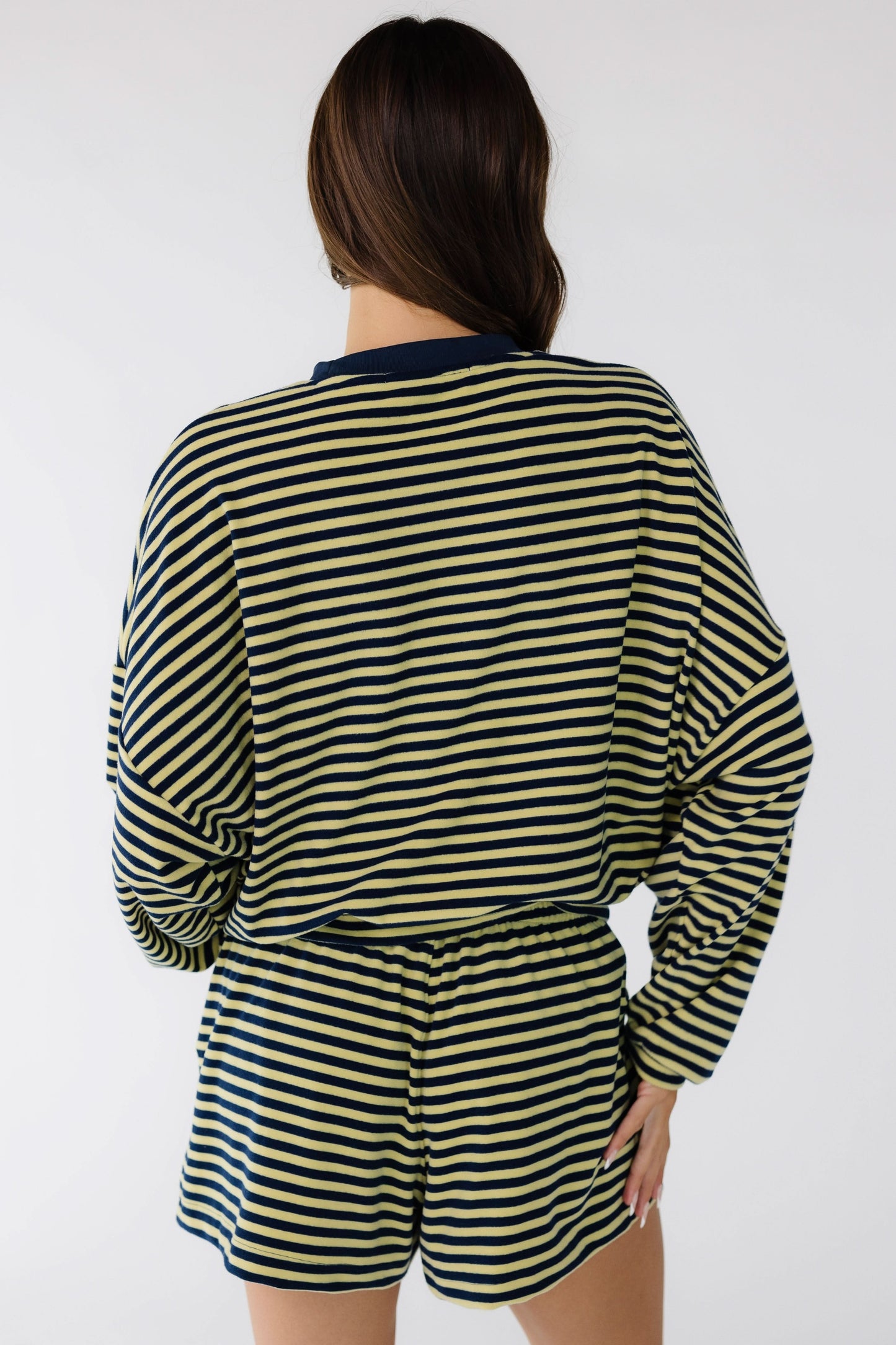 Back view of a woman wearing a navy & yellow stripe short set with long sleeves and elastic waist.