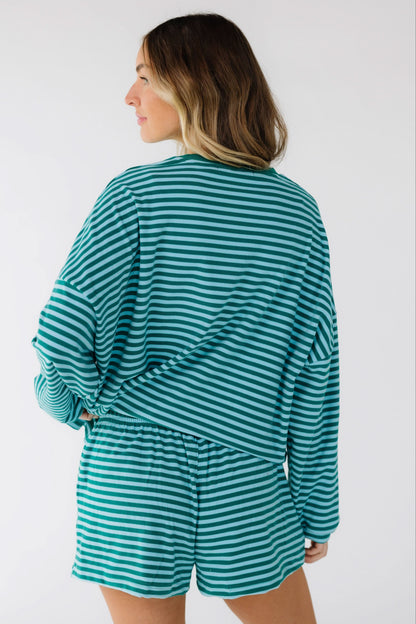 Back view of a woman wearing a loose fitting stripe shorts set in green & blue.