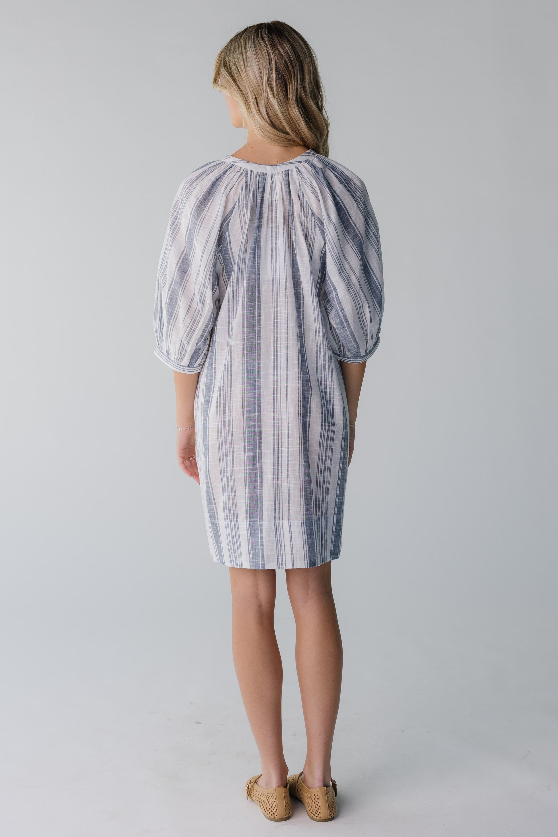 Back view of white and blue stripe knee length dress with three quarters length sleeves