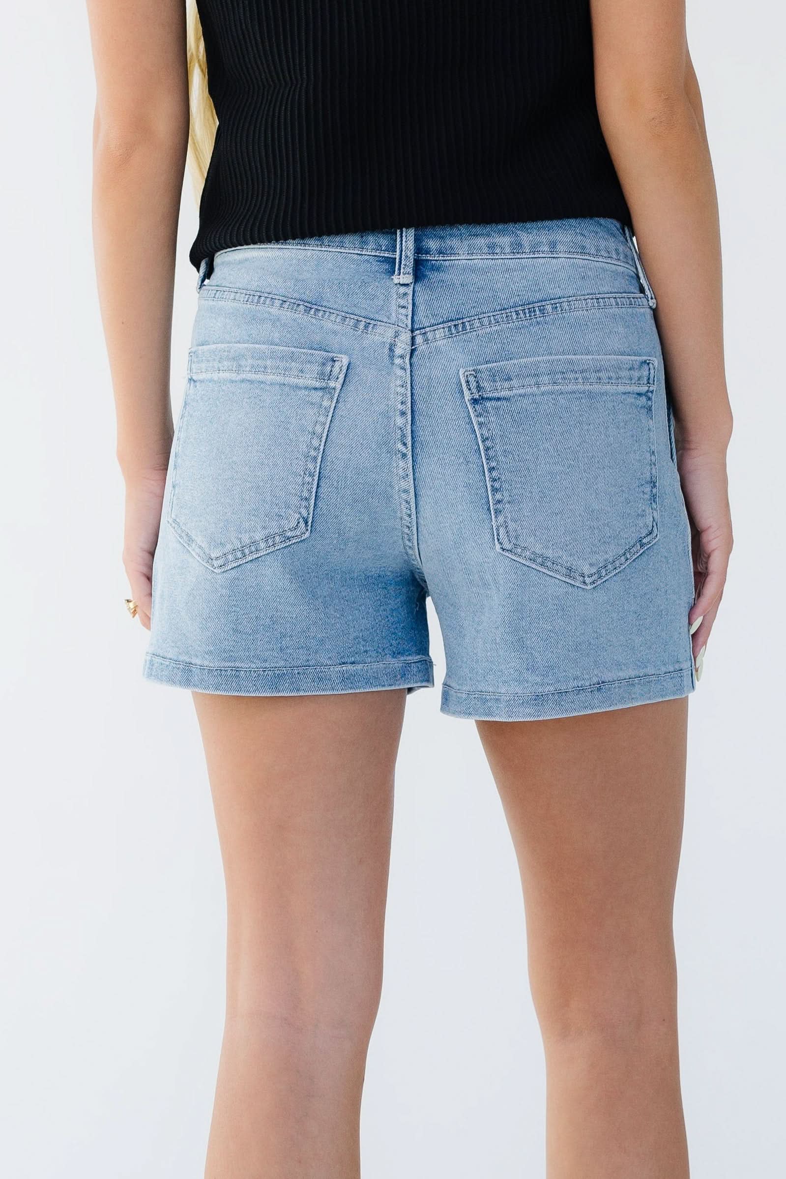Back view of a woman wearing light denim shorts with large back pockets.