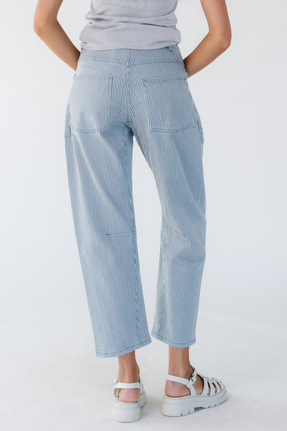 Back view of a young woman wearing blue & white stripe barrel jeans with back pockets.