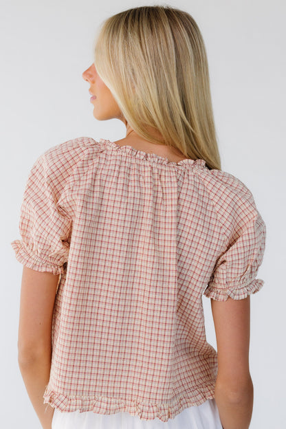 Back view of a woman wearing a loose fitting red plaid blouse with short puff sleeves.