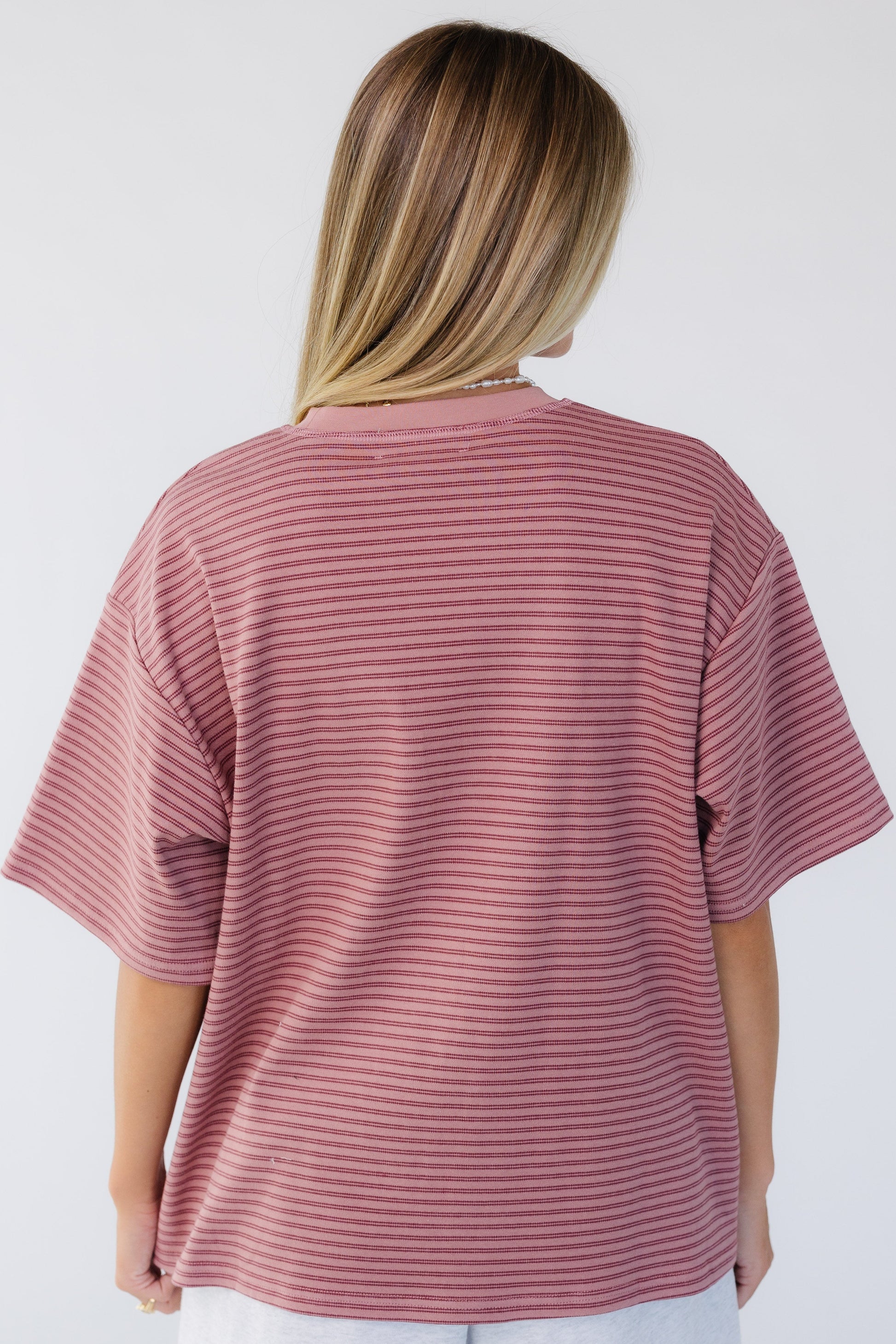 Back view of a woman wearing a short sleeve, loose fitting tee.