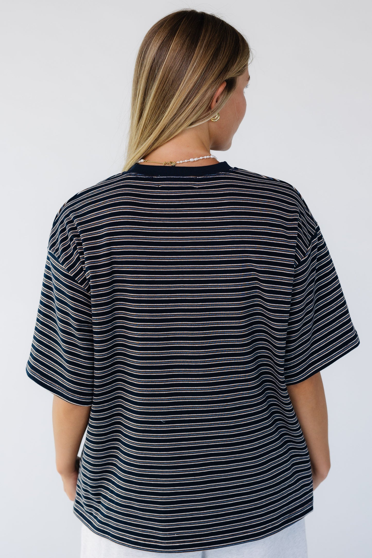 Back view of a woman wearing a navy stripe short sleeve tee.