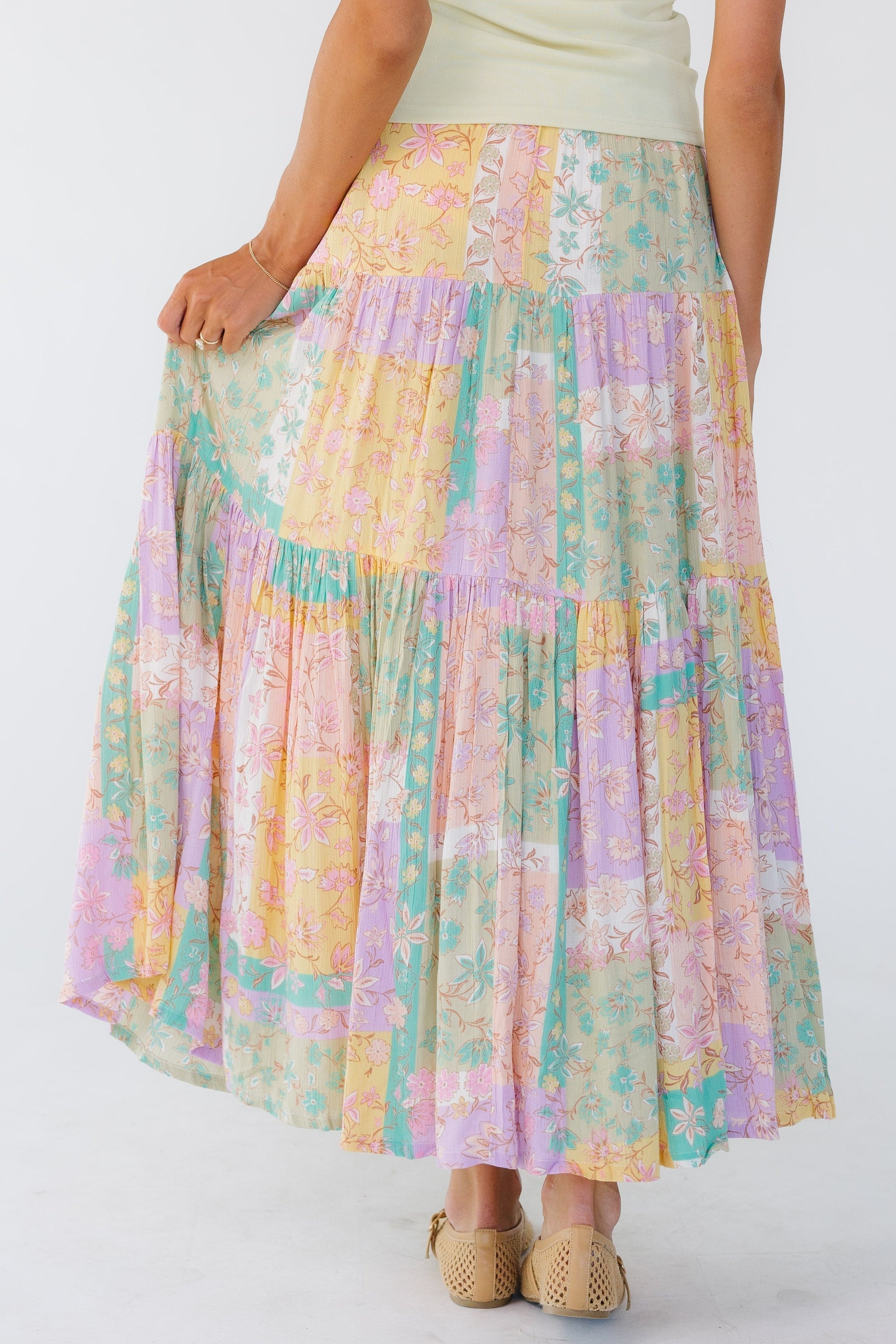 Back view of a woman wearing a pastel tiered midi skirt by Billabong.