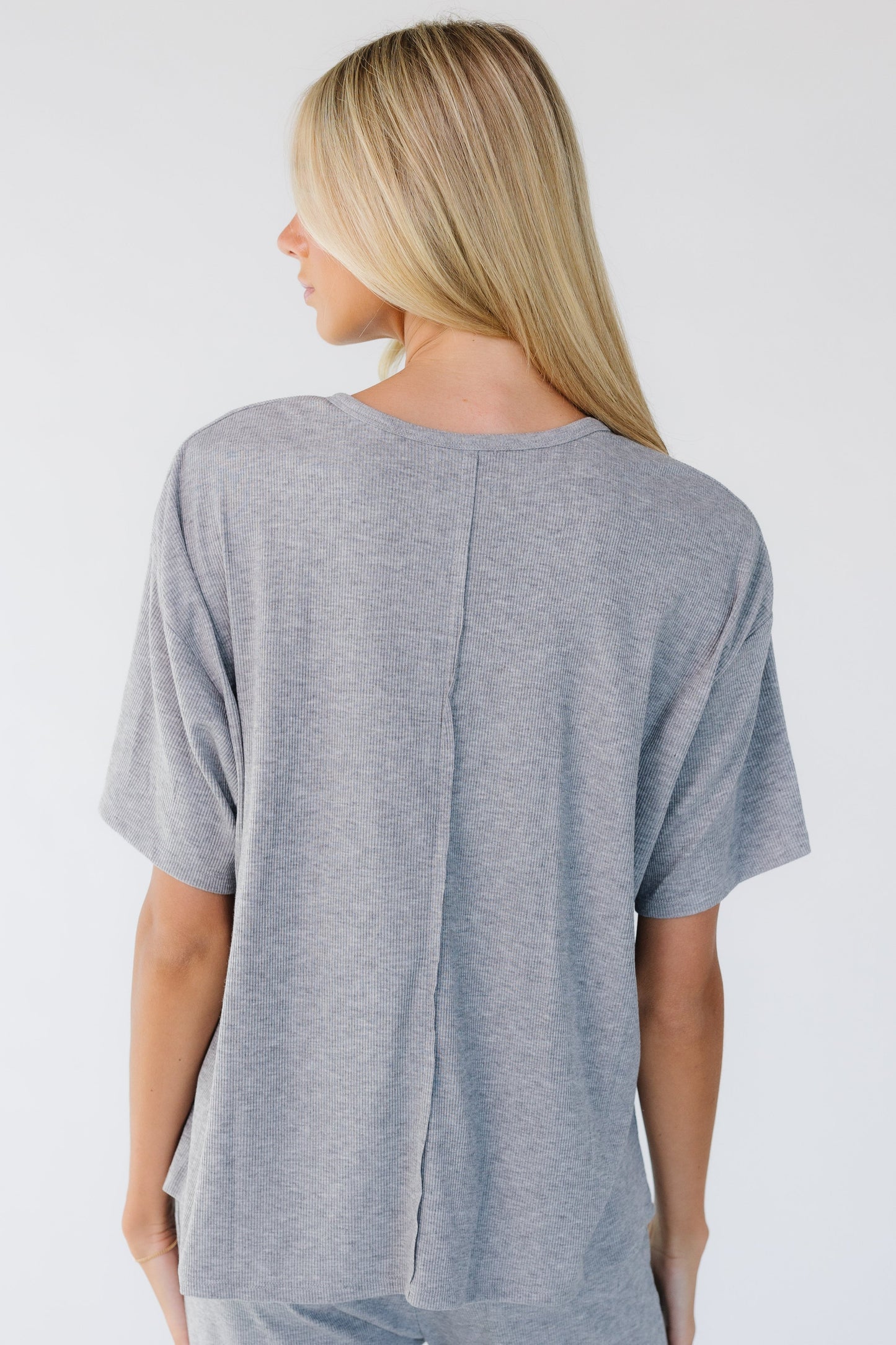 Back view of a woman wearing a loose fitting grey top.
