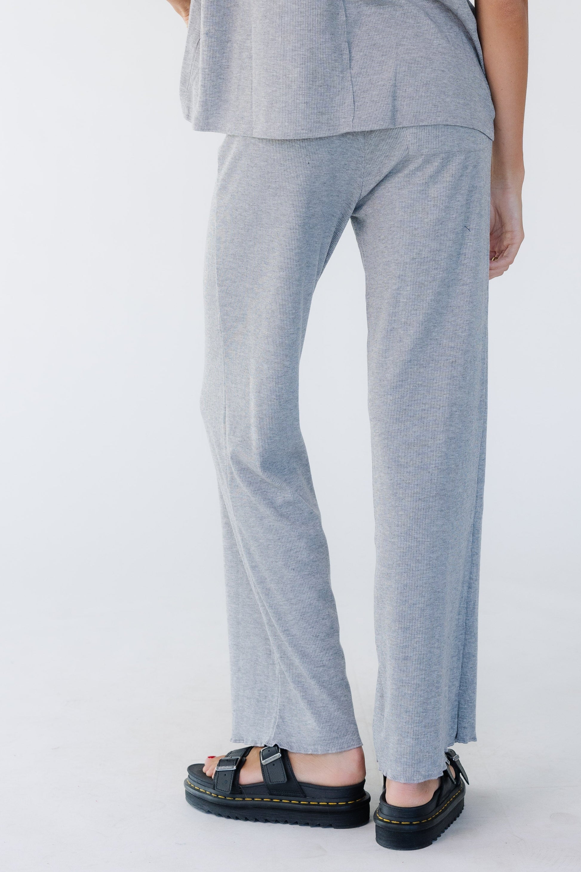 Back view of a woman wearing a pair or light grey, rib knit lounge pants with a wide cut leg.
