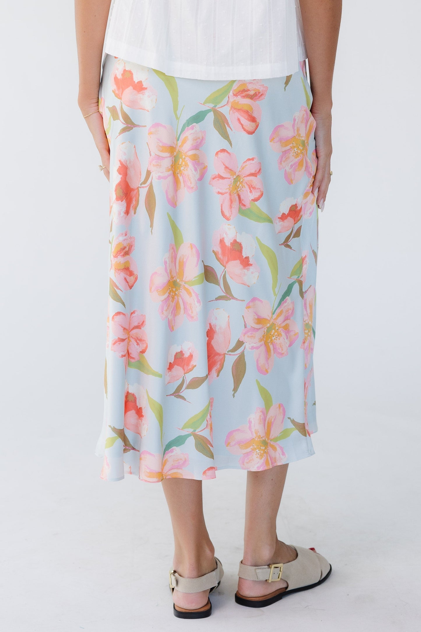 Back view of a young woman wearing a light blue floral A-line midi skirt.