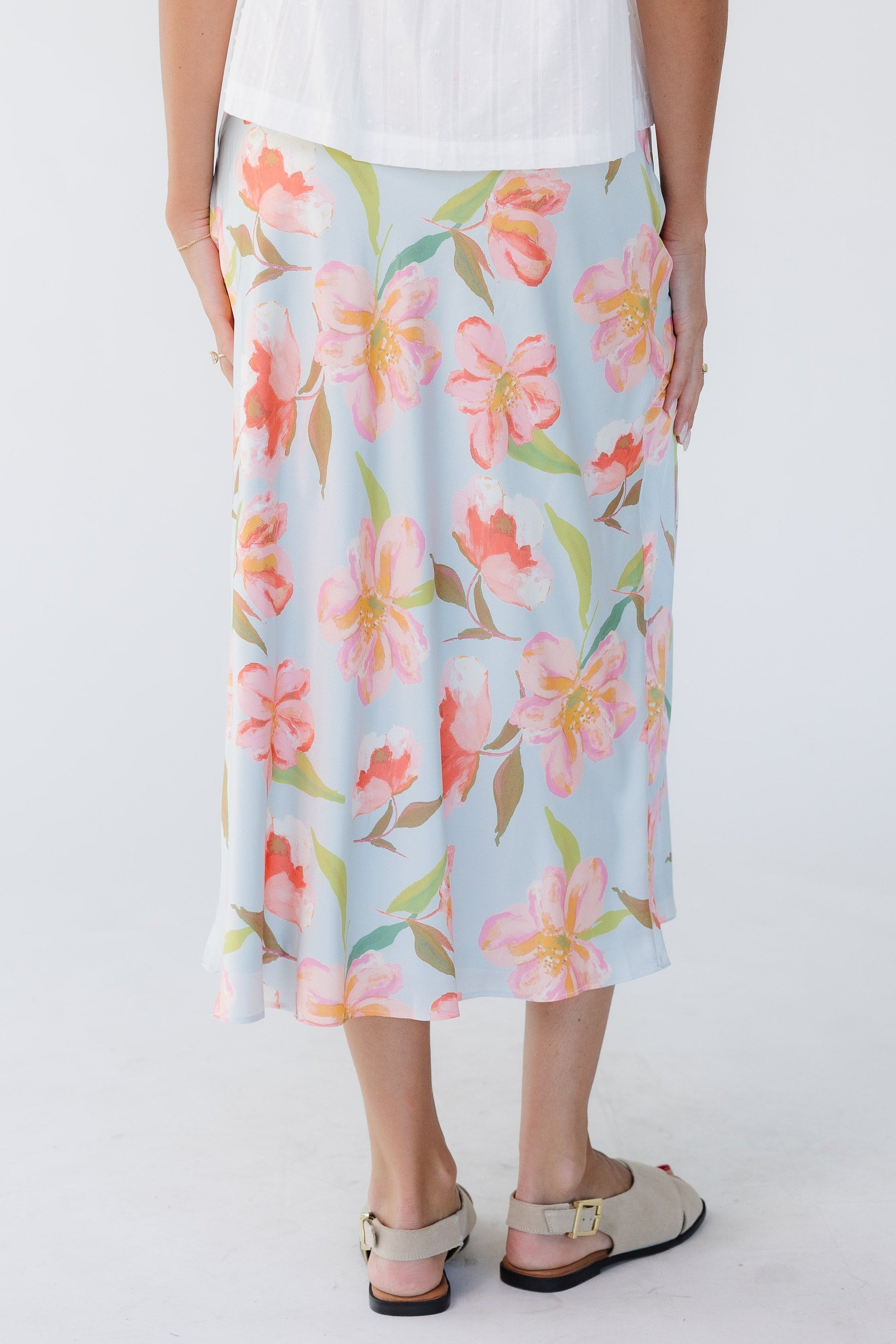 Back view of a young woman wearing a light blue floral A-line midi skirt.
