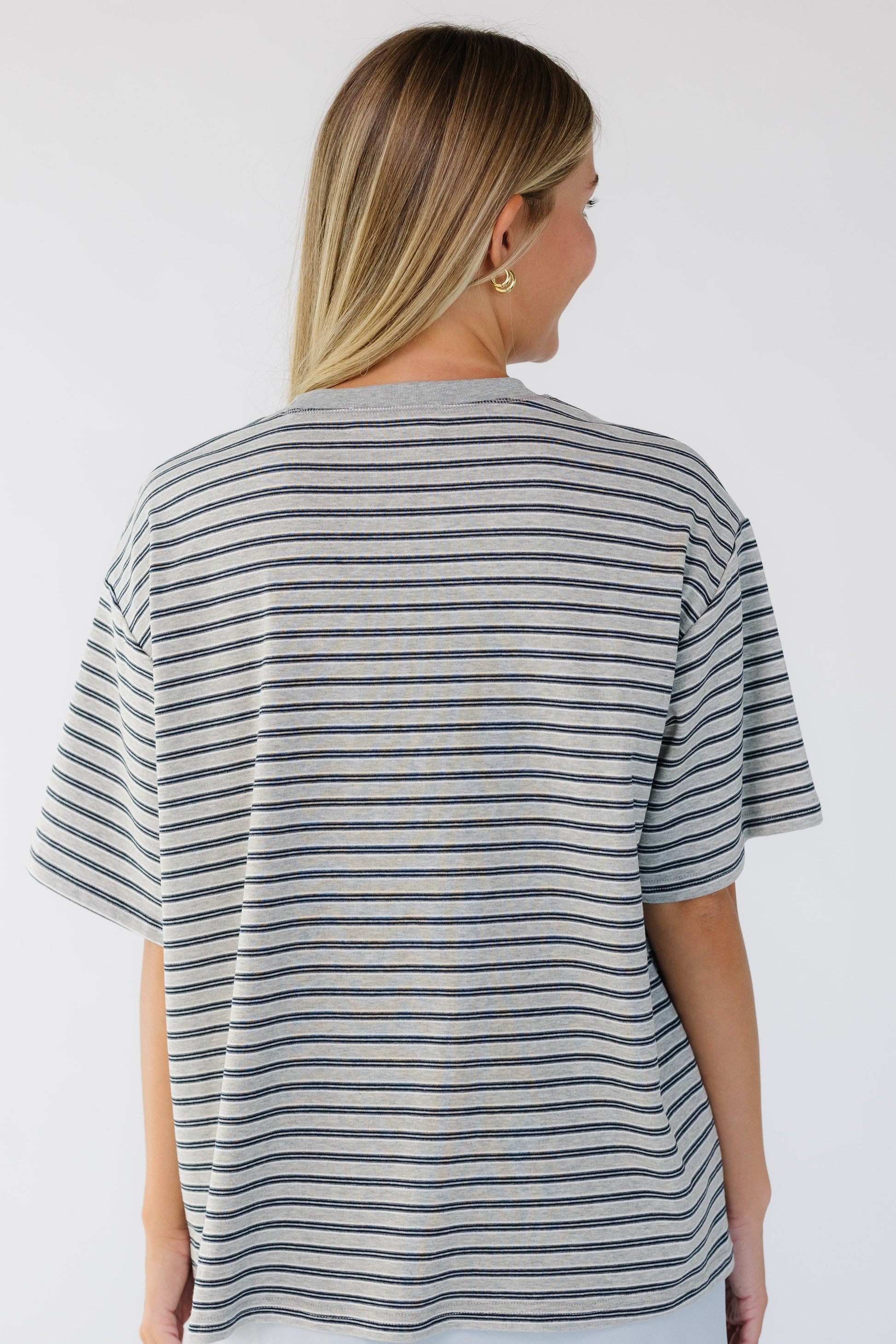 Back view of a woman wearing a grey stripe, short sleeve tee.