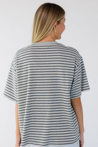 Back view of a woman wearing a grey stripe, short sleeve tee.