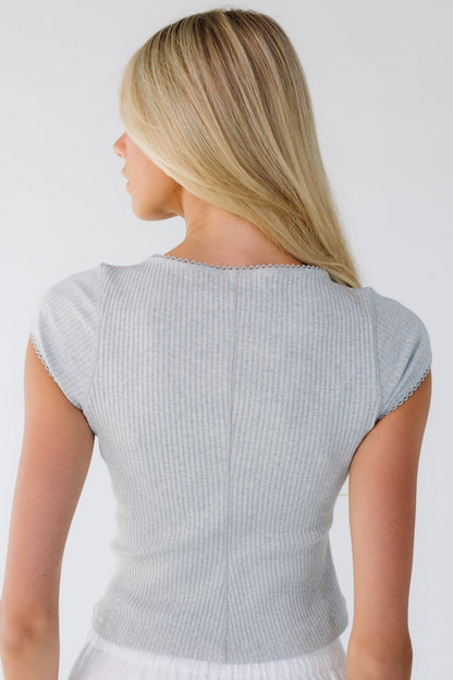 Back view of a woman wearing a close fitting rib knit top with cap sleeves.