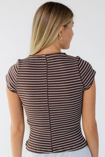 Back view of a woman wearing a brown & white stripe close fitting top with short sleeves.