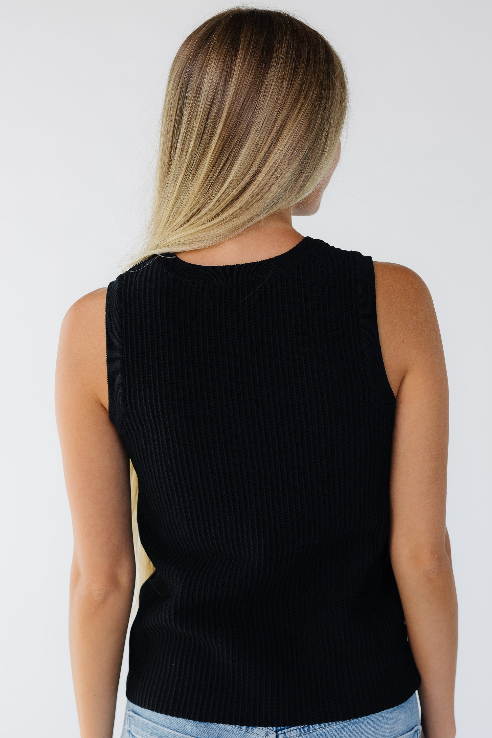 Back view of a woman wearing a black tank top with a ridged stripe texture.