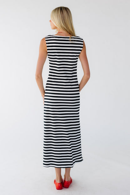 Back view of a woman wearing a sleeveless black & white stripe midi-maxi dress.