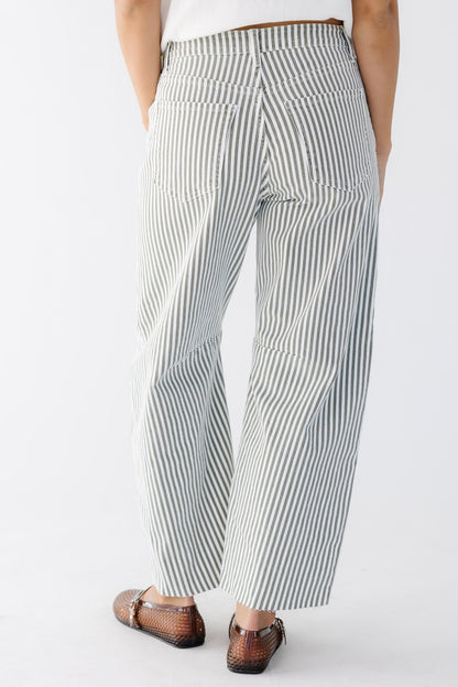 Back view of a woman wearing olive and white stripe barrel jean with pockets.