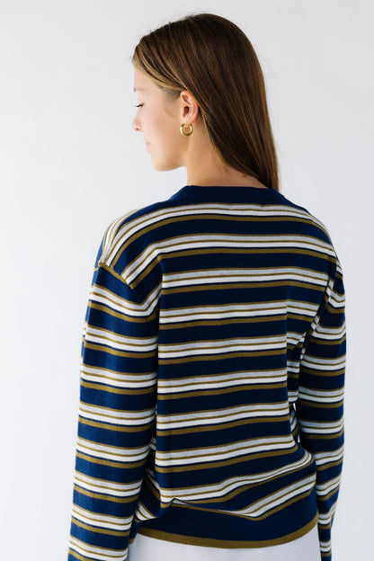 Back view of a woman searing a navy & multi-color stripe loose fitting sweater.